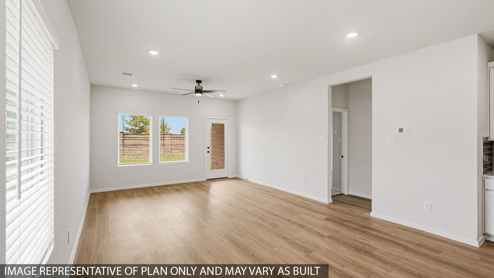 Open kitchen with an island, stainless steel appliances, white cabinets, white walls, and vinyl wood flooring.