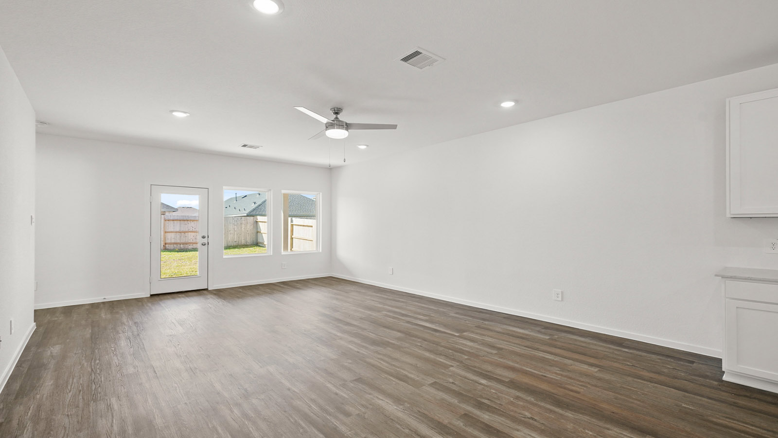 Living room looking to kitchen, dining, outdoor areas in this new home features natural light, with fresh open concept flow