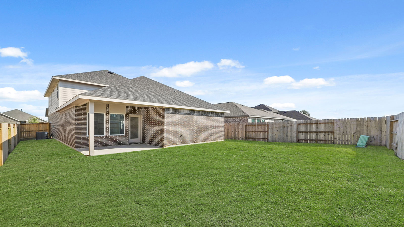 Backyard in this new home with full lawn, covered concrete patio, and fencing potential for added privacy