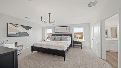 Primary bedroom with windows, white walls, and light carpet.