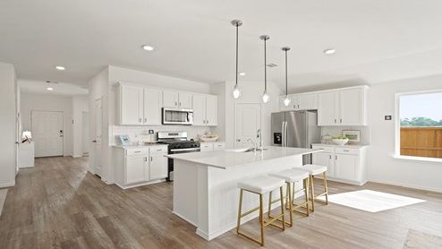 Open kitchen with an island, pendant lighting, back splash, white cabinets, white walls, and vinyl wood flooring.