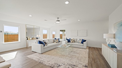 Open living room with windows, white walls, and vinyl wood flooring.
