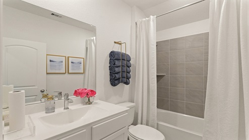 Secondary bathroom with a shower and tub combo, white walls, and vinyl wood flooring.