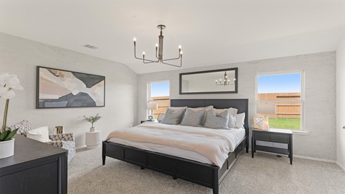 Primary bedroom with windows, white walls, and light carpet.