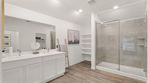 Primary bathroom with dual sinks, shower, tub, white walls, white cabinets, and vinyl wood flooring.
