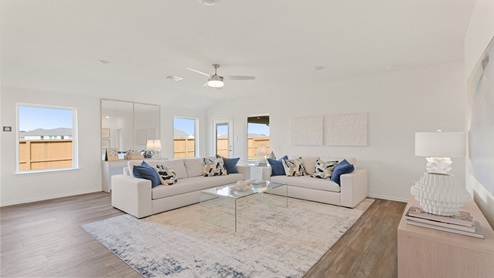 Open living room with windows, white walls, and vinyl wood flooring.
