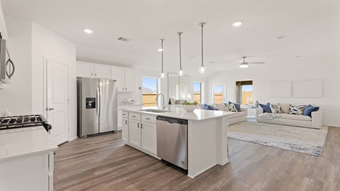 Open kitchen with an island, pendant lighting, back splash, white cabinets, white walls, and vinyl wood flooring.