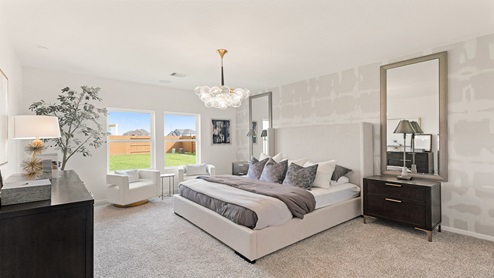 Primary bedroom with windows, white walls, and light carpet.