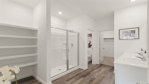 Primary bathroom with dual sinks, a shower, a tub, white cabinets, white walls, and vinyl wood flooring.