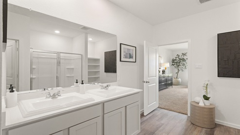 Primary bathroom with dual sinks, a shower, a tub, white cabinets, white walls, and vinyl wood flooring.