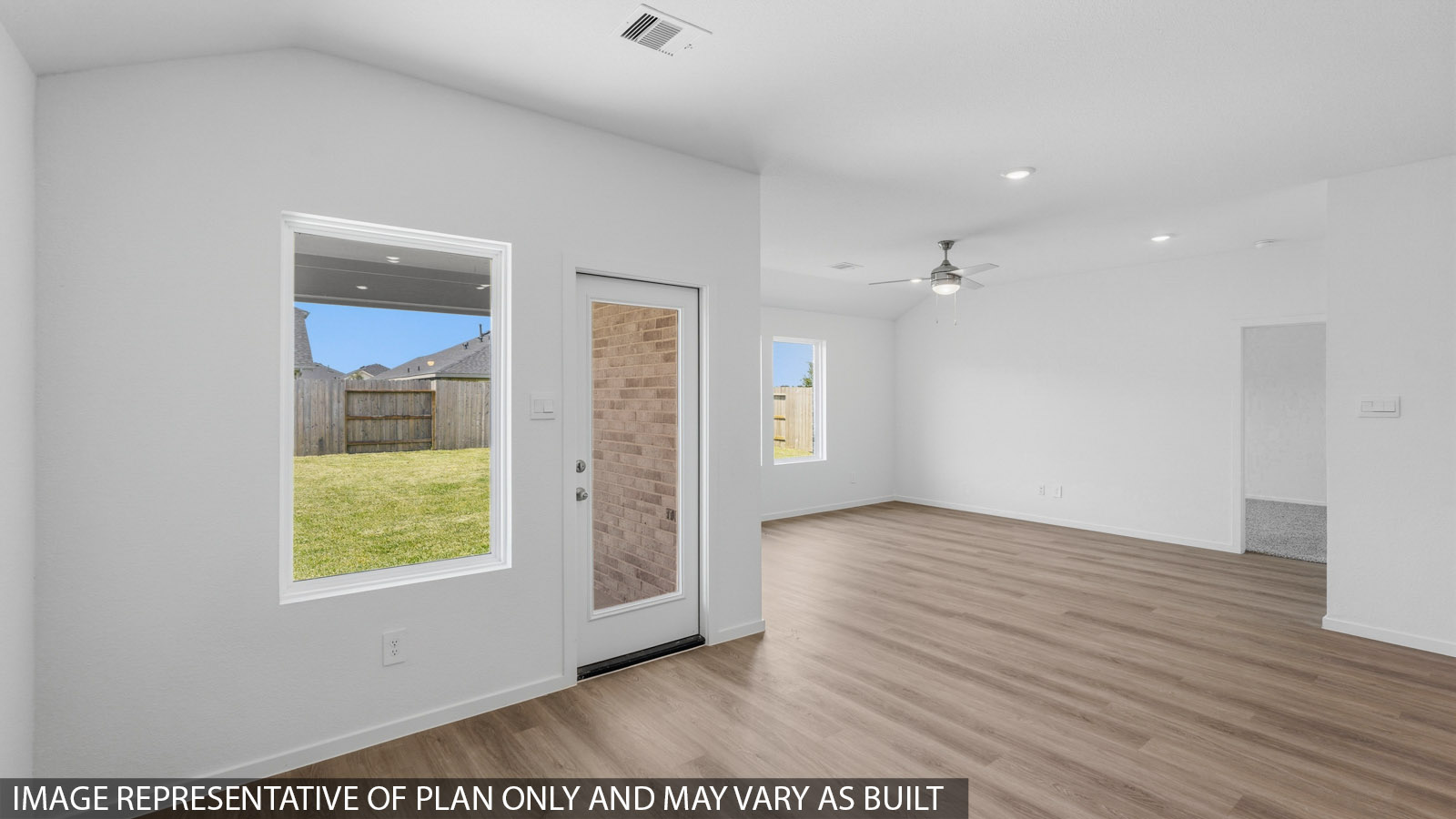 Open living room with white walls, windows, and vinyl wood flooring.