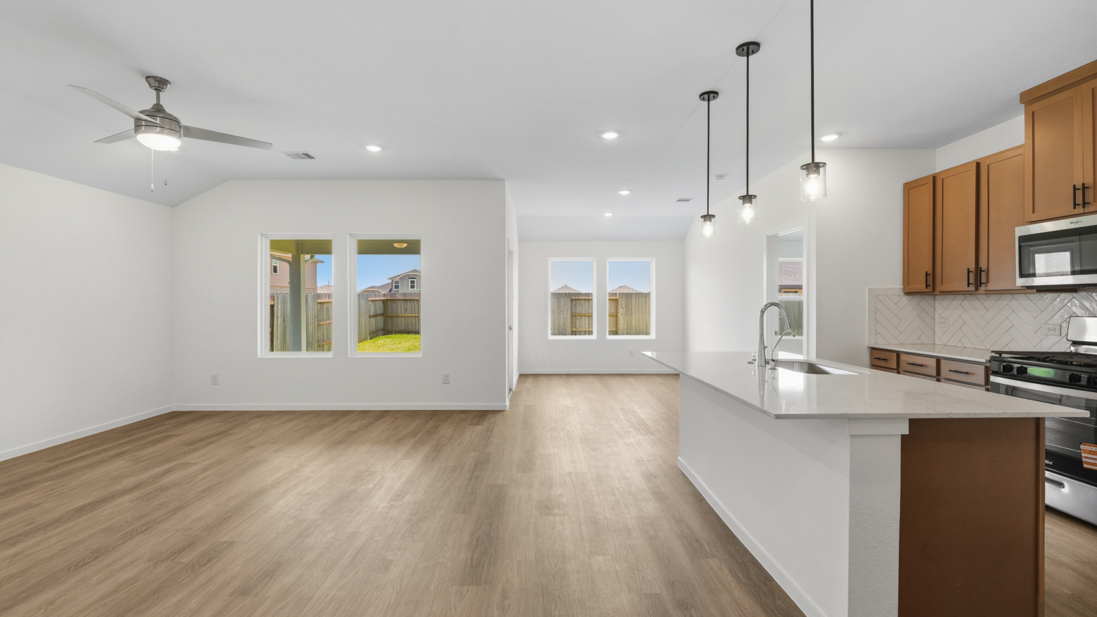 open concept living and dining area with vinyl flooring, quartz countertops, and stainless steel appliances