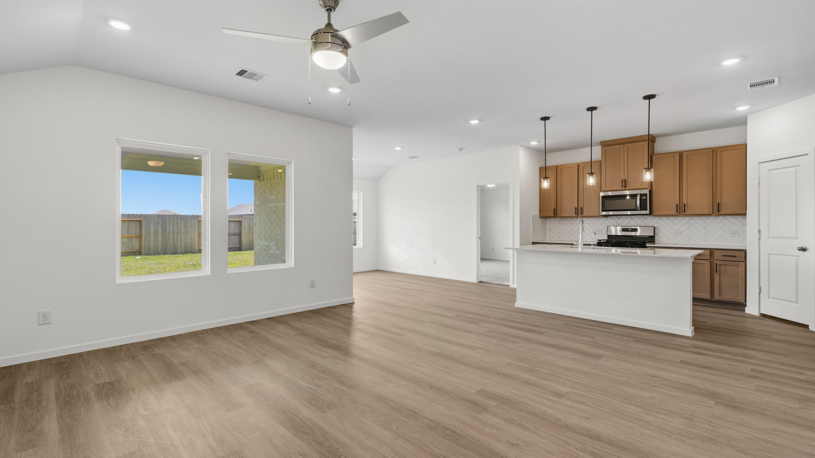 open concept living and dining area with vinyl flooring, quartz countertops, and stainless steel appliances