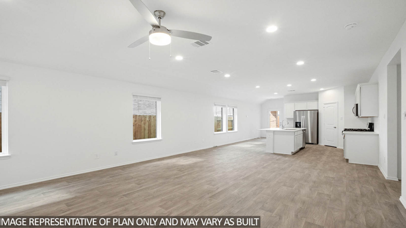 Open living room with windows, white walls, and vinyl wood flooring.