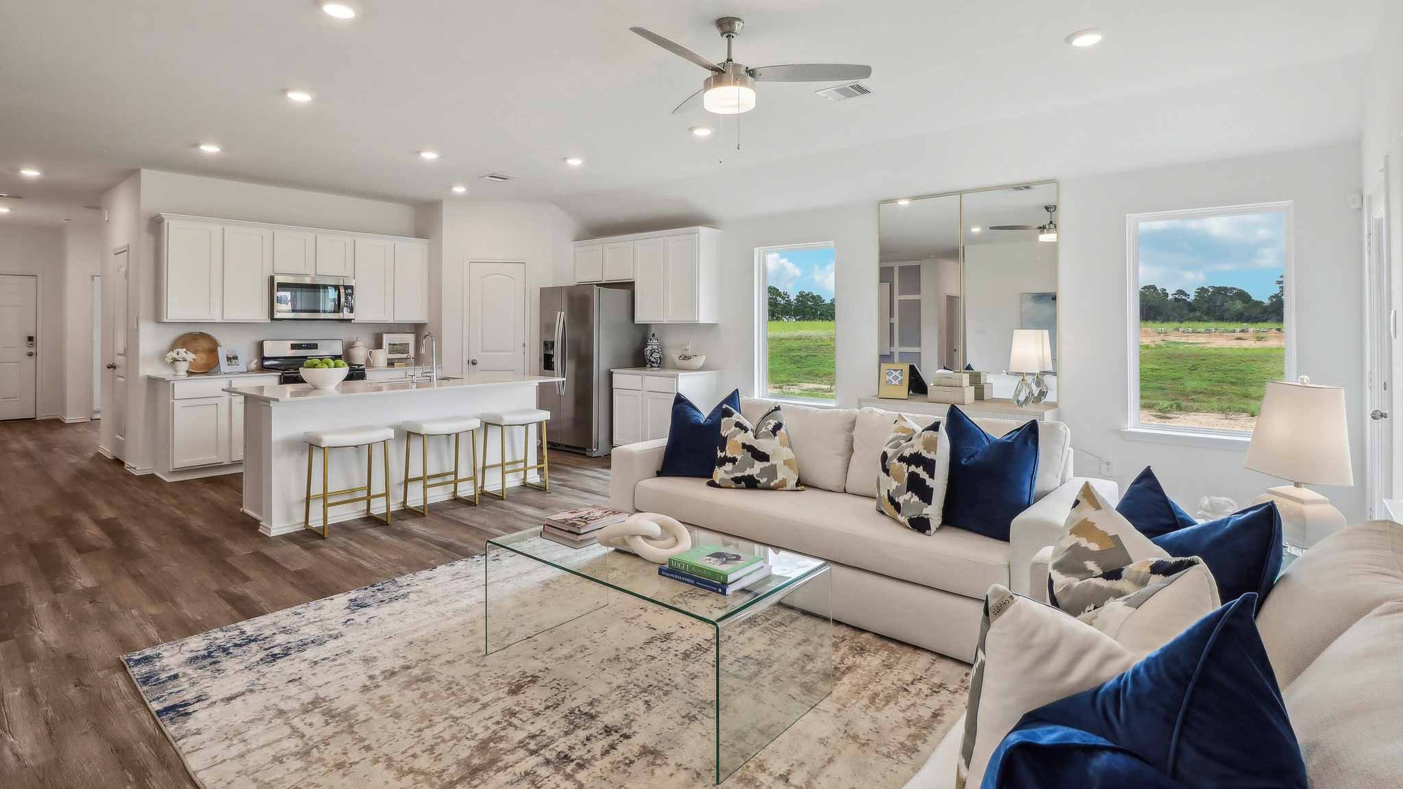 Open living room with windows, white walls, and vinyl wood flooring.