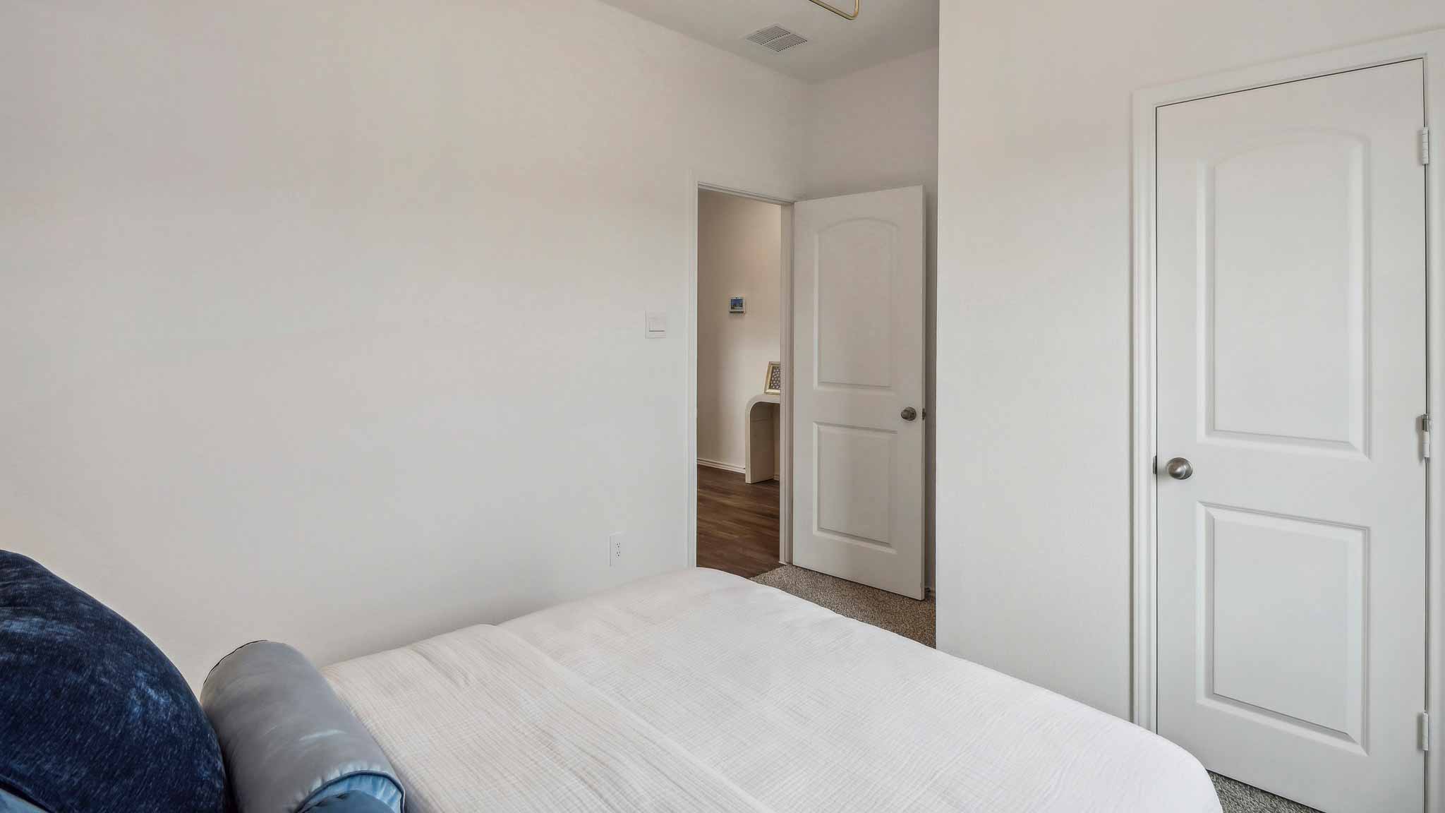 Secondary bedroom with windows, white walls, and vinyl wood flooring.