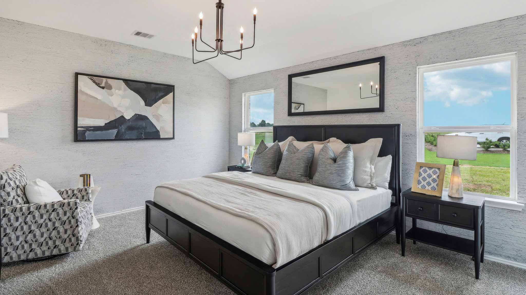 Primary bedroom with windows, white walls, and light carpet.