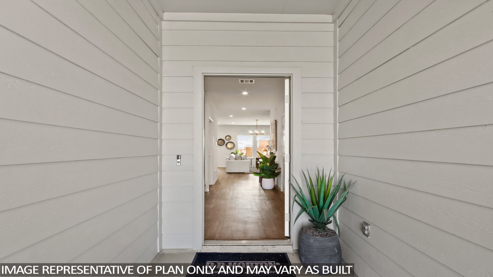 Entryway with light colored siding and a potted plant at the door.