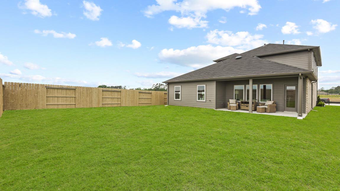 Large backyard with grass and covered patio.