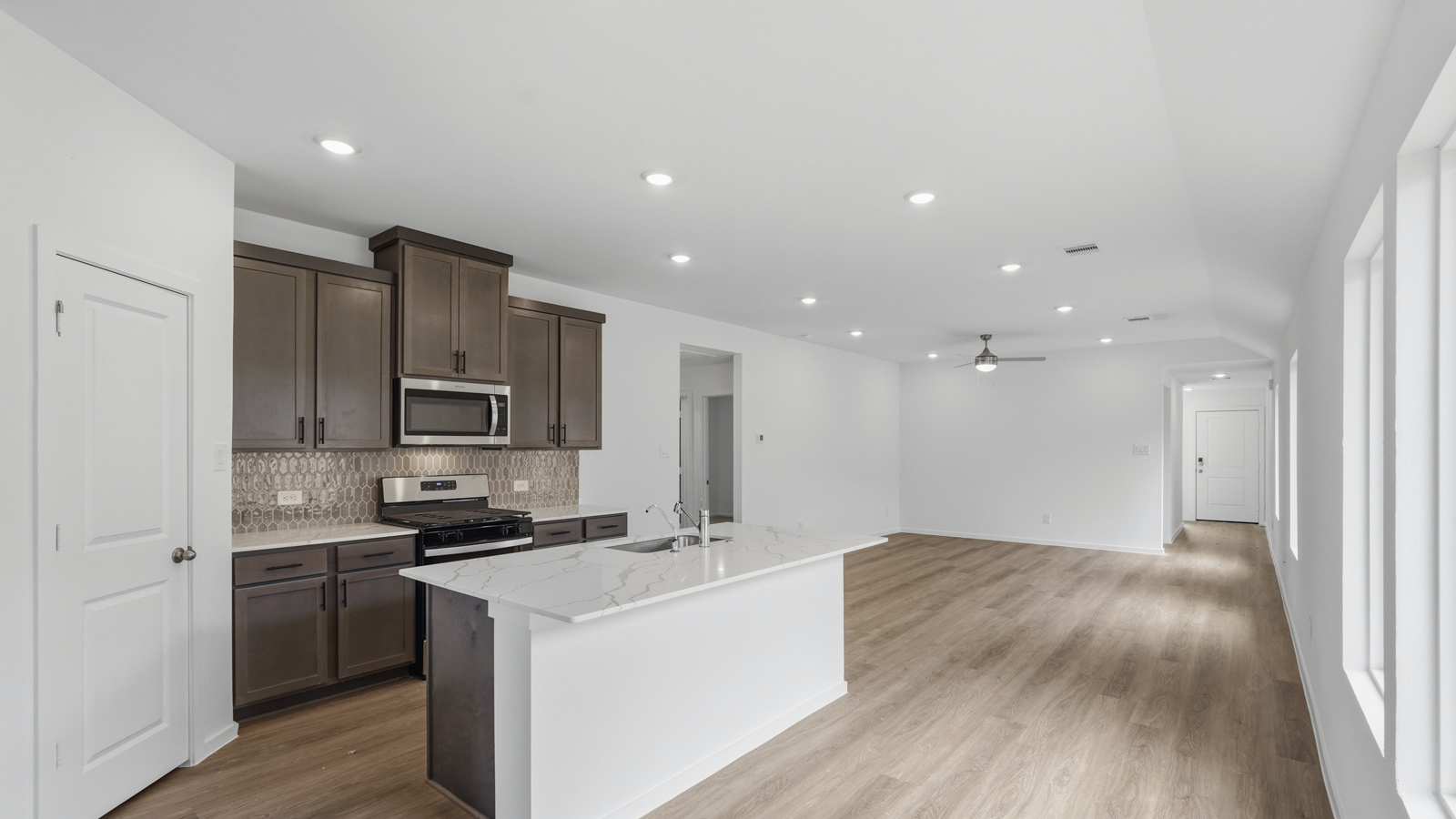 open concept living and dining area with backsplash, quartz countertops, and stainless steel appliances