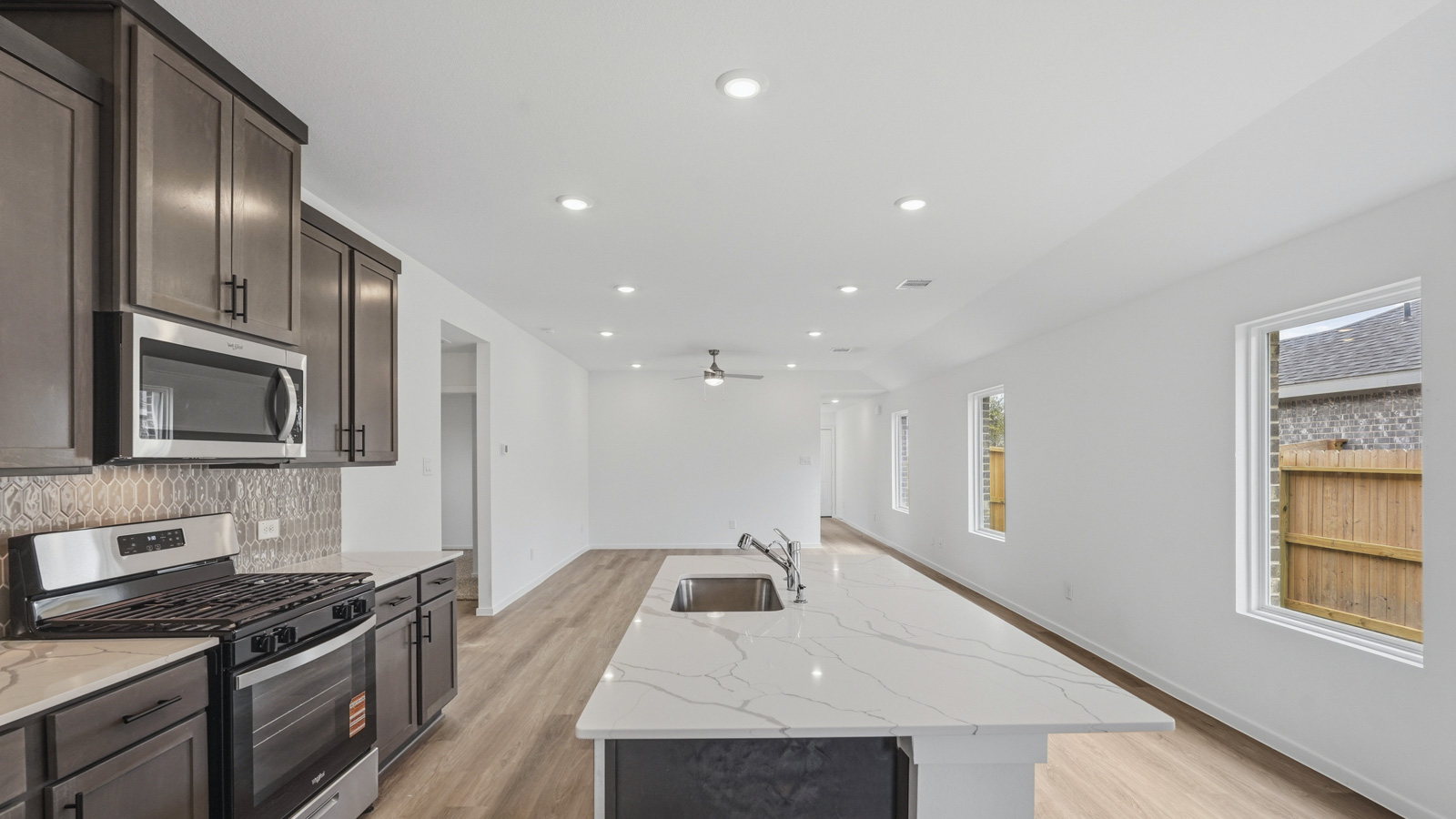 open concept living and dining area with backsplash, quartz countertops, and stainless steel appliances