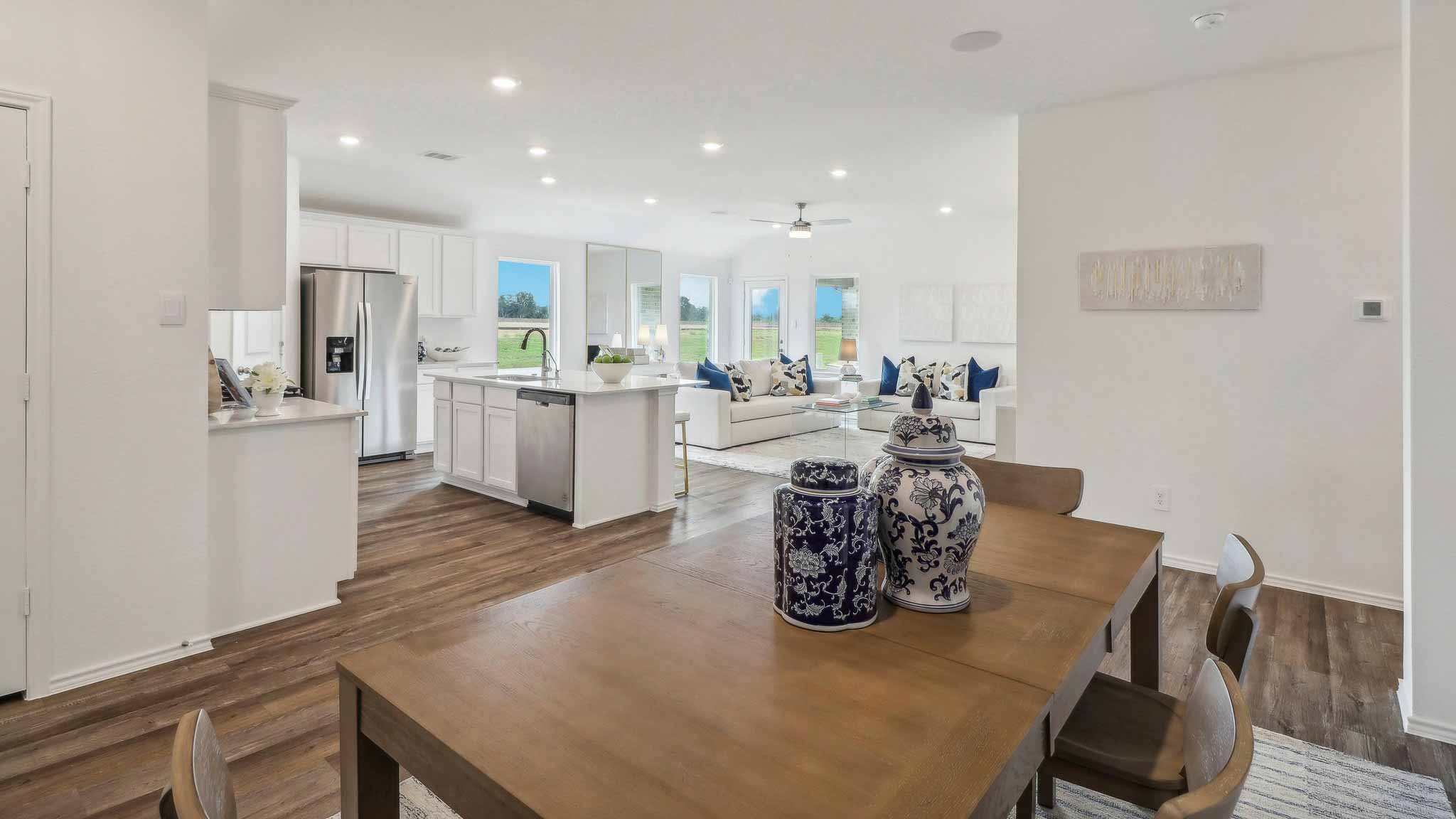 open concept living and dining area with vinyl flooring, large windows, and quartz countertops