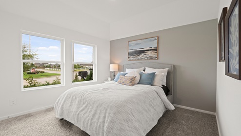 Secondary bedroom with windows, white walls, and light carpet.