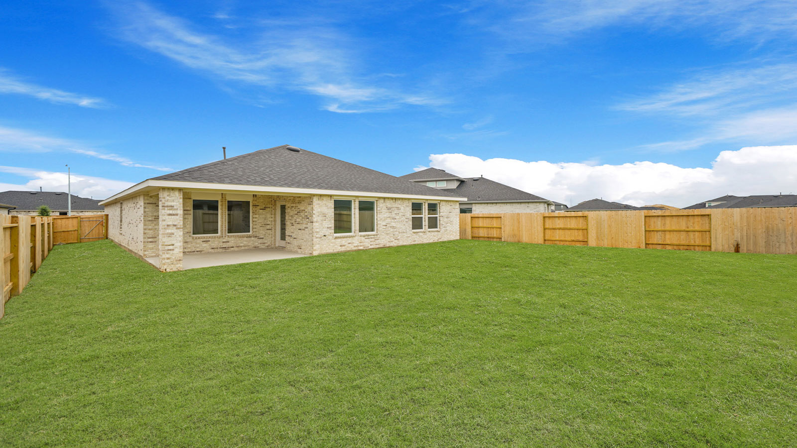Backyard with a covered concrete patio offering room for seating, grill setup, and a transition from indoor to outdoor living