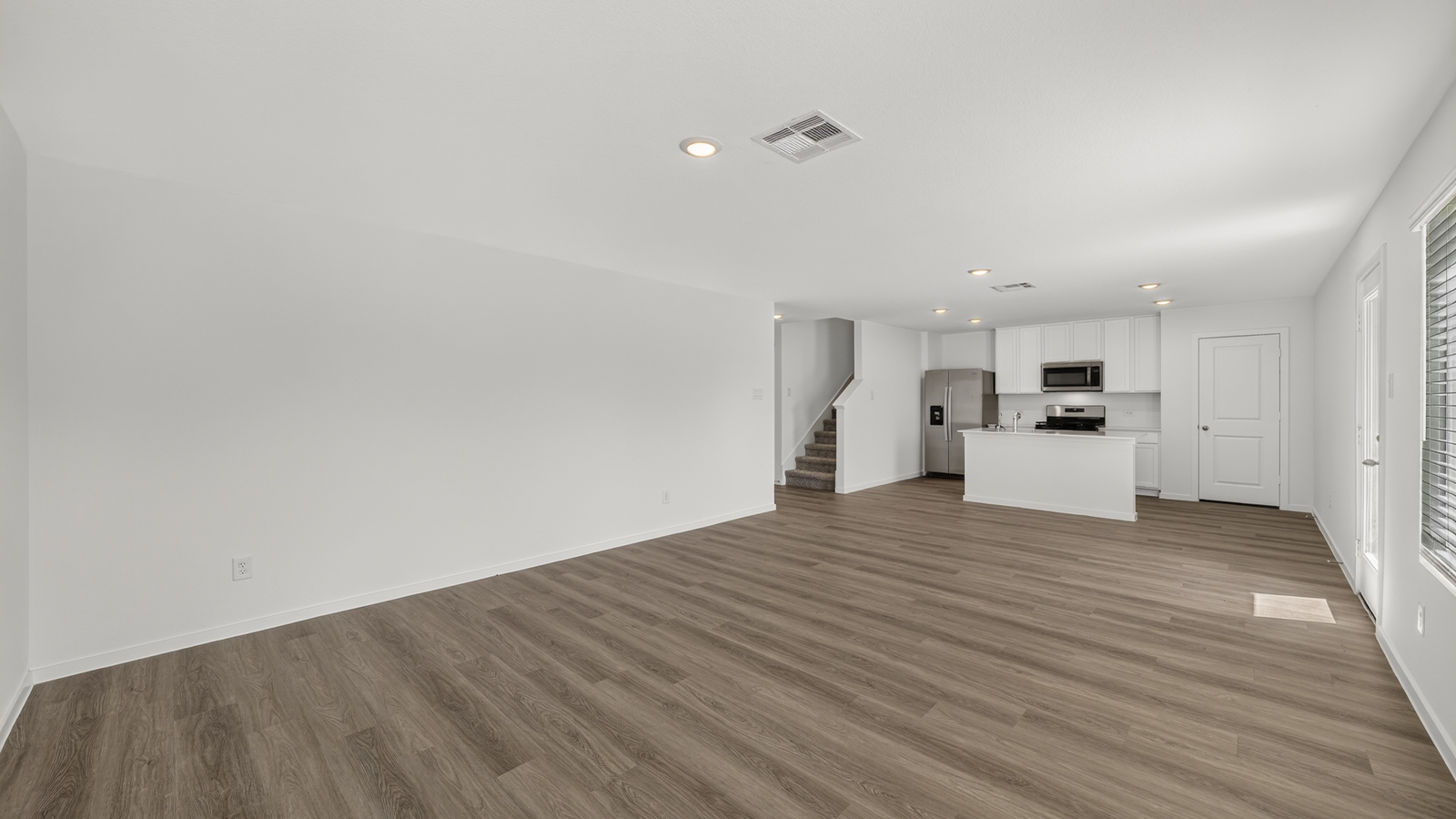 open concept living and dining area with vinyl flooring, quartz countertops, and stainless steel appliances