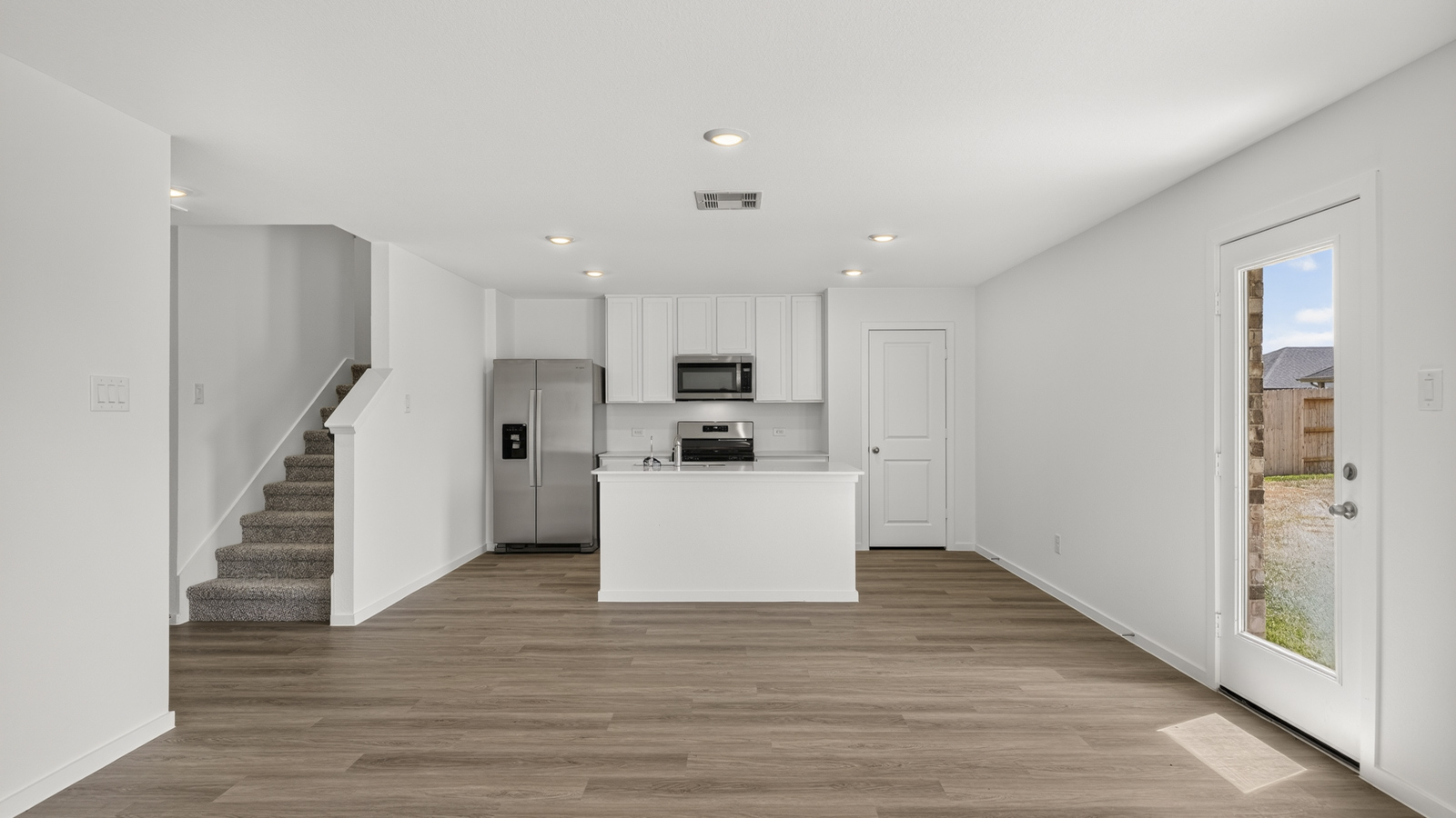 open concept living and dining area with vinyl flooring, quartz countertops, and stainless steel appliances