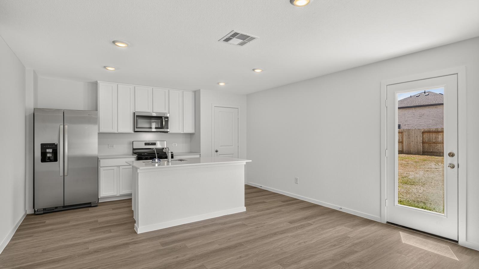 open concept living and dining area with vinyl flooring, quartz countertops, and stainless steel appliances
