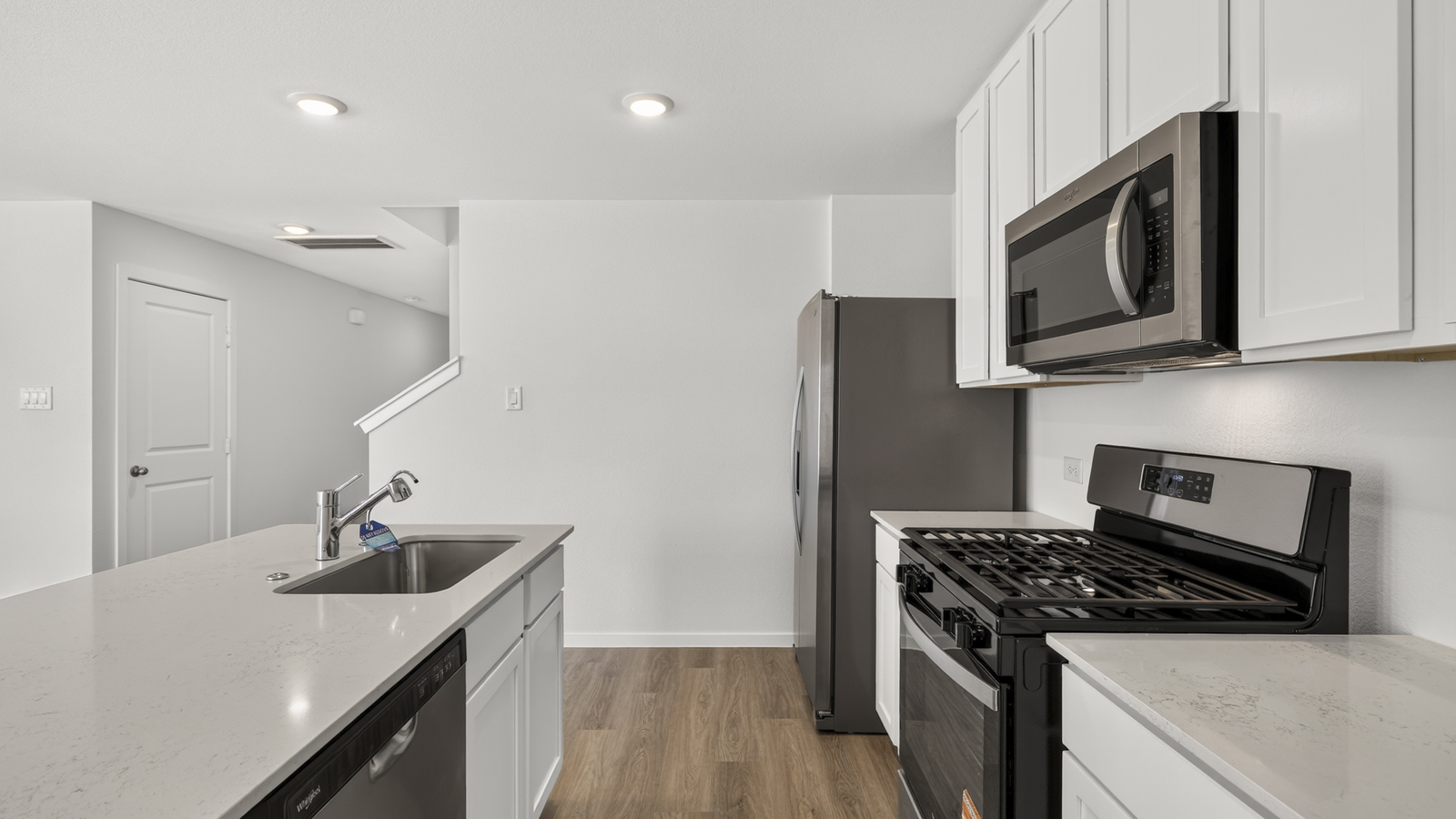 open concept living and dining area with vinyl flooring, quartz countertops, and stainless steel appliances
