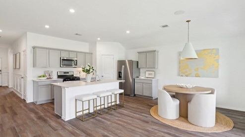 kitchen and dining area with stainless steel appliances, quartz countertops, and vinyl flooring