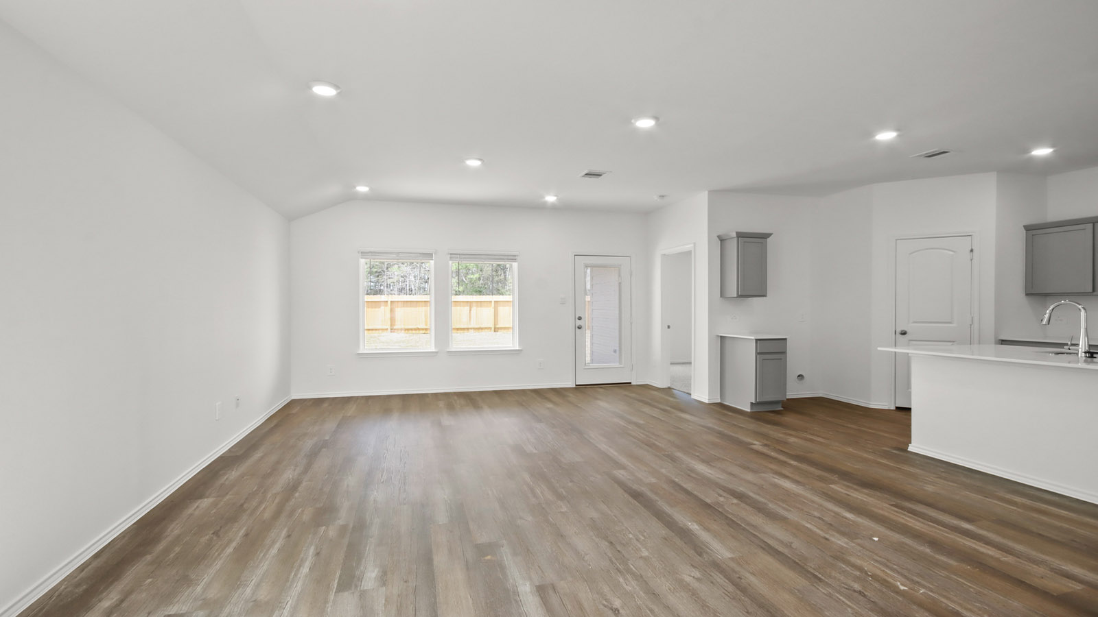open concept living and dining area with vinyl flooring, quartz counertops, and large windows