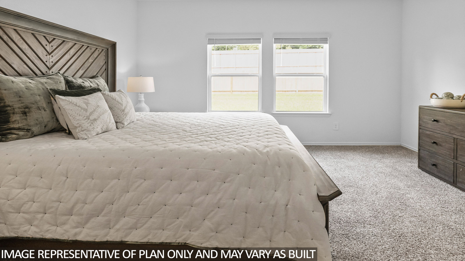 Primary bedroom with white walls, light carpet, and windows.