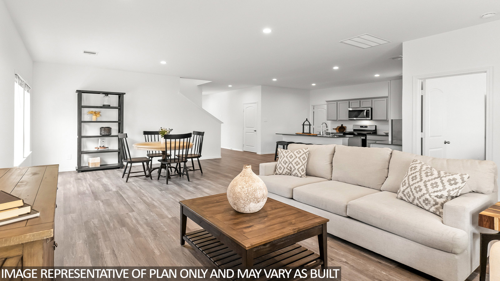 Open living room with windows, white walls, and vinyl wood flooring.