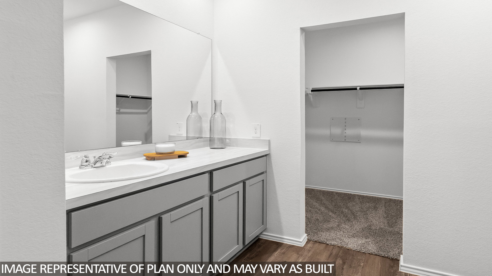 Primary bathroom with a walk-in shower, dual sinks, light gray cabinets, white countertops,vinyl wood flooring, and white walls.