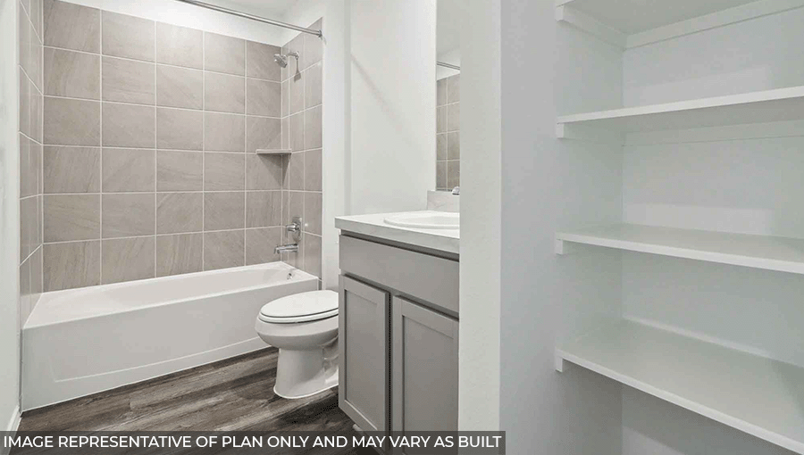Secondary bathroom with a shower and tub combo, a singular sink, light gray cabinets, storage shelves, white walls, and vinyl wood flooring.