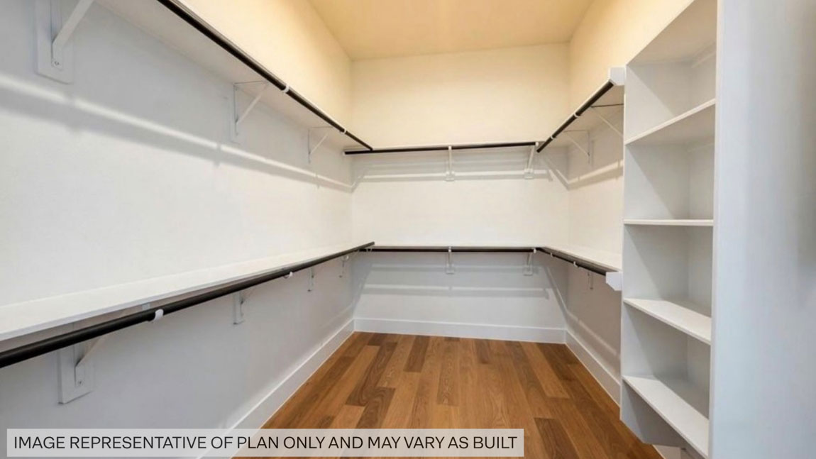 Primary bedroom walk-in closet with vinyl flooring in Butlers Bend Estates community in Pinehurst  TX