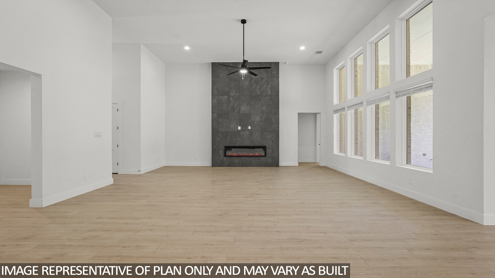 Open concept living, dining, and kitchen area with vinyl flooring and bright windows with floor to ceiling fireplace