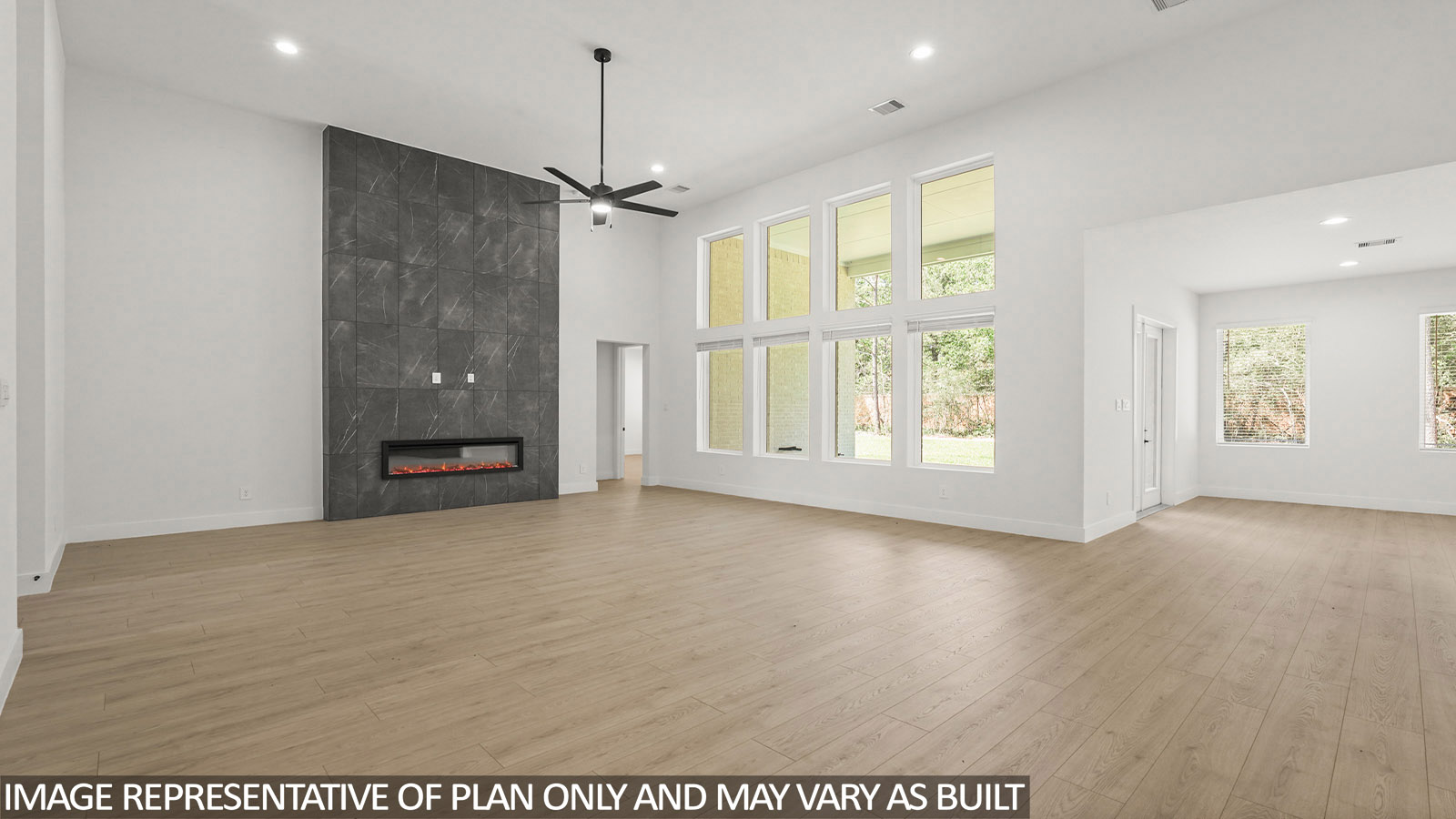 Open concept living, dining, and kitchen area with vinyl flooring and bright windows with floor to ceiling fireplace