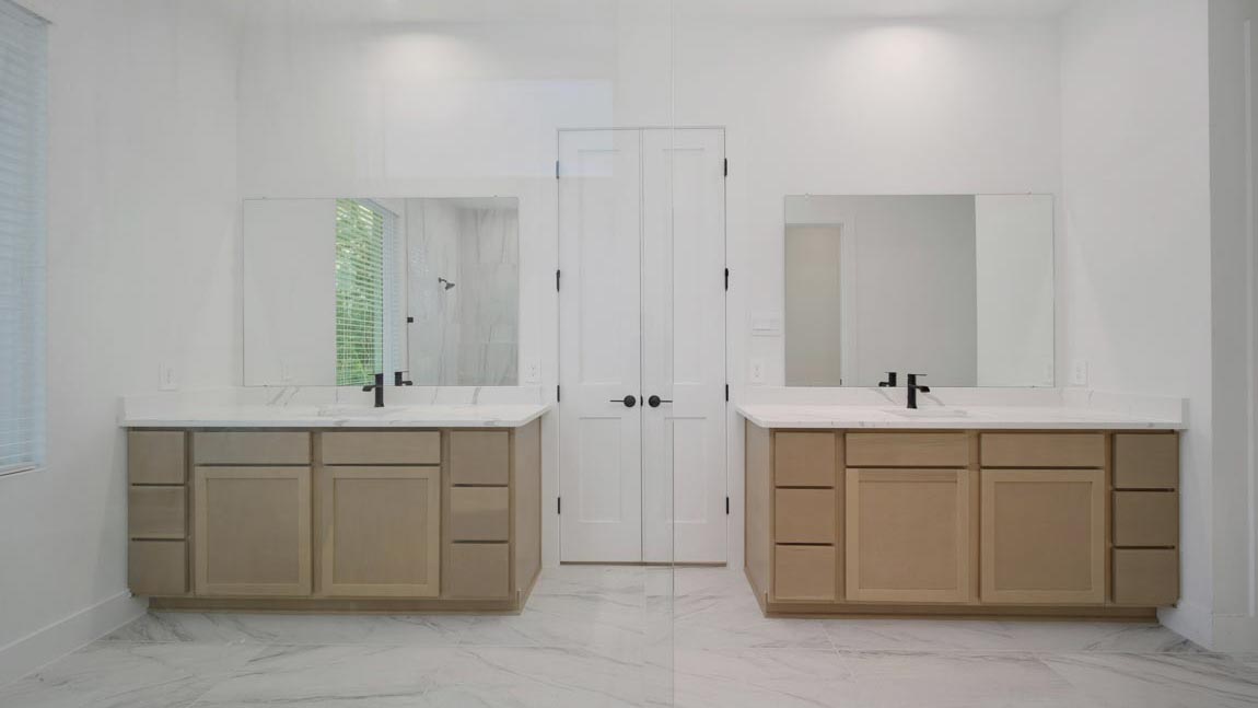 Primary bathroom with double sinks with quartz counter tops and tile floor in Pinehurst TX