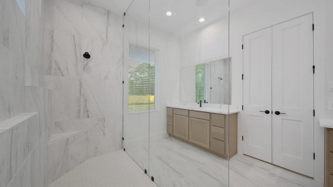 Primary bathroom with super shower with tiled wall and semi frameless glass in Pinehurst  TX