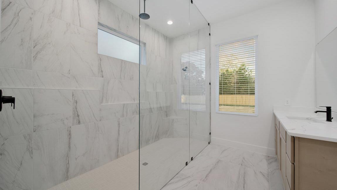 Primary bathroom with super shower with tiled wall and semi frameless glass in Pinehurst  TX