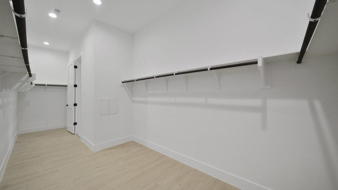 Primary bedroom walk-in closet with vinyl flooring in Butlers Bend Estates community in Pinehurst  TX