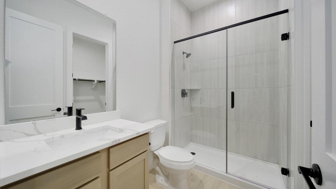 Secondary bathroom with stand alone shower with tile and semi frameless glass quartz counter tops in Pinehurst  TX