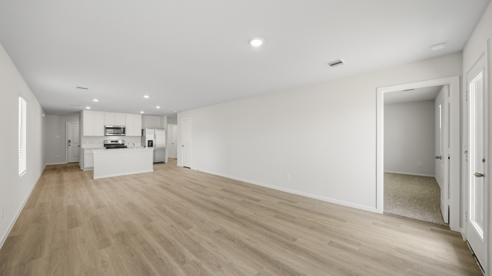 open concept living and dining area with vinyl flooring, quartz countertops, and stainless steel appliances