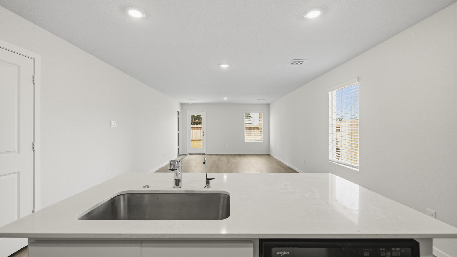 open concept living and dining area with vinyl flooring, quartz countertops, and stainless steel appliances