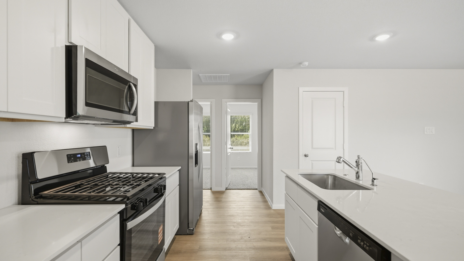 open concept living and dining area with vinyl flooring, quartz countertops, and stainless steel appliances