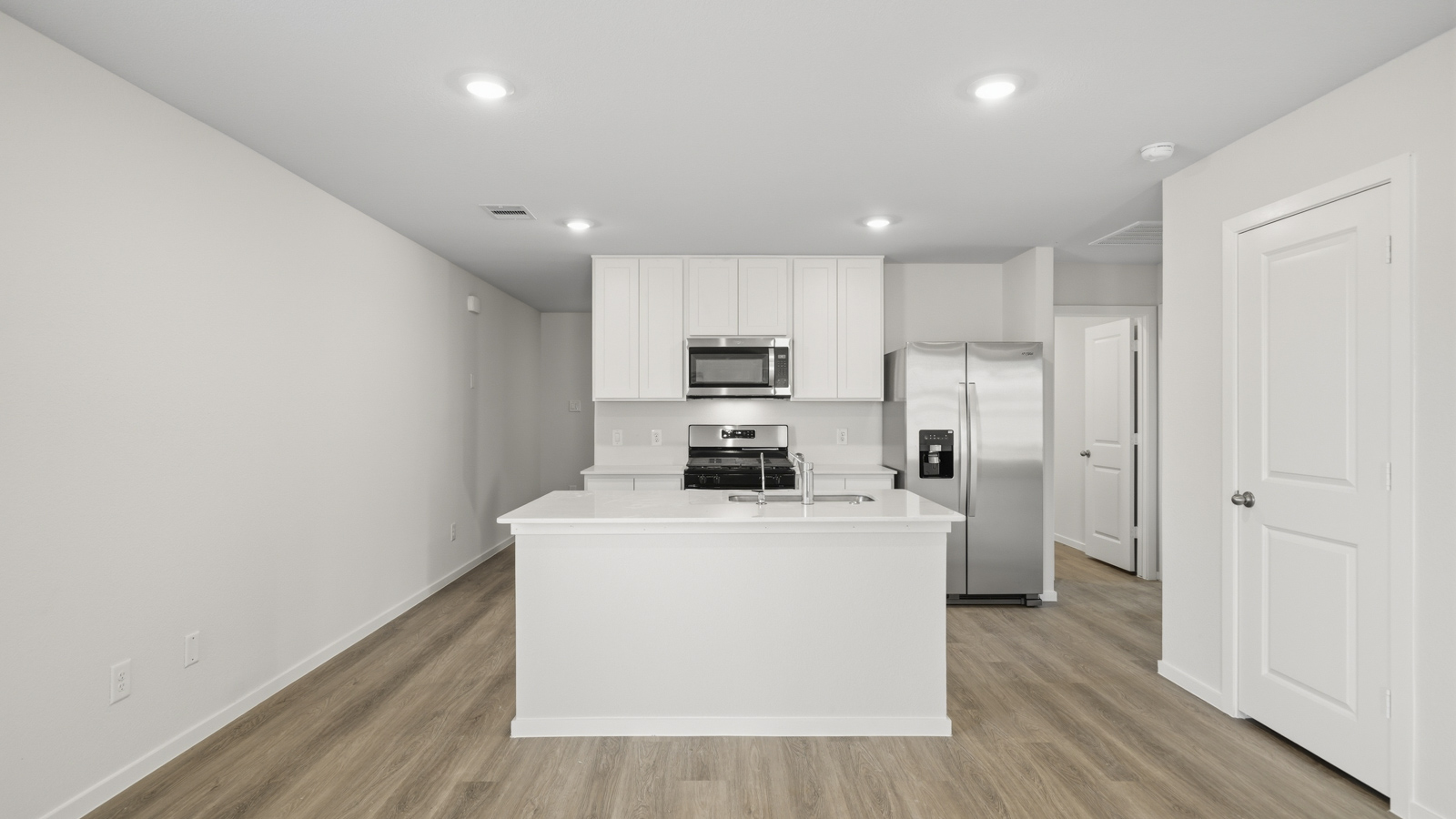 open concept living and dining area with vinyl flooring, quartz countertops, and stainless steel appliances